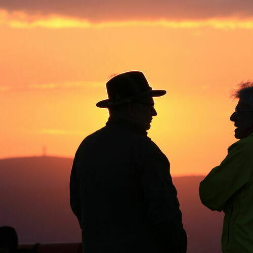 Unterhaltung zwischen zwei Mnnern, whrend im Hintergrund die Sonne aufgeht.