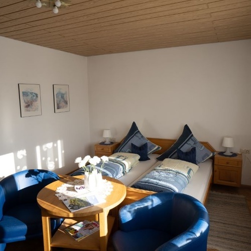 Doppelbett davor steht ein Tisch und zwei Sessel  - 